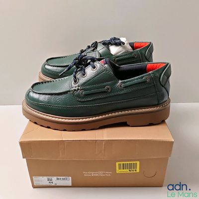 chaussures bateau en cuir vert pour homme, à semelles rouges, posées sur une boîte en carton
