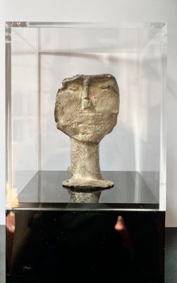 a glass display case with a stone head inside of it