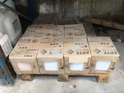 Plusieurs cartons de vin sont empilés sur des palettes dans un entrepôt