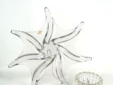 un vase en verre et un bougeoir en verre posés sur une surface blanche