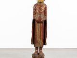 une statue en bois représentant un Bouddha debout sur un socle