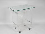a clear glass side table with wheels on a white background