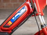 a close up of a red motorcycle with a blue, yellow, and red sticker on it
