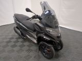 un scooter noir garé sur un sol à damier