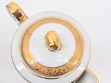 gold and white porcelain teapot with a gold handle