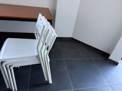 quatre chaises blanches disposées devant une table