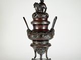 un vase antique en bronze surmonté d'un oiseau