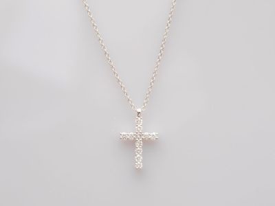 un pendentif en forme de croix avec un diamant blanc, monté sur une chaîne en argent