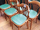 six chaises en bois avec des assises en cuir vert, placées devant une fenêtre