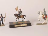 three figurines of soldiers on horses and a horse with a flag