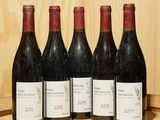 six bouteilles de vin sont alignées sur un tonneau en bois