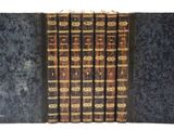 un lot de cinq livres aux reliures dorées, empilés les uns sur les autres