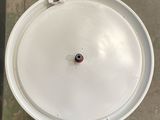 a white bowl with a red button sitting on a tile floor