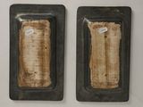pair of black metal plates with a piece of bread in the middle of them