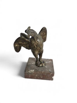 statue d'un oiseau posée sur un socle en marbre, sur fond blanc