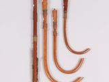 four wooden walking canes are lined up on a white surface