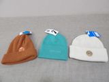 three beanies are sitting on a couch with tags on them