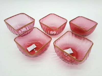 six bols en verre rose aux bords dorés posés sur une surface blanche