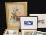 several framed and unframed art pieces are displayed on a black table