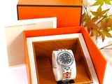 a watch in a box with a plant in the background