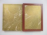 two books with gold and red covers sitting on top of each other