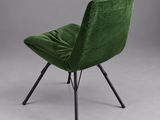 a green velvet chair with black legs and a black metal frame