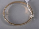 a gold bangle with a white button on it