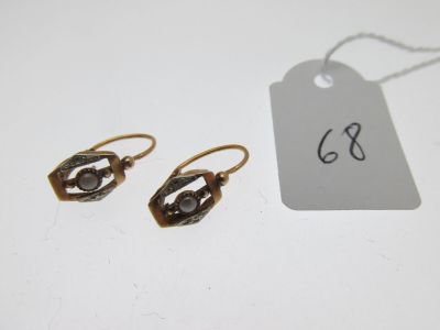 deux paires de boucles d'oreilles et une étiquette posées sur une table blanche
