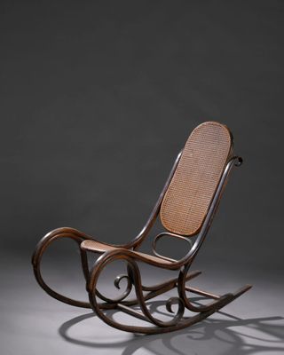un vieux fauteuil à bascule avec une assise en osier sur fond gris