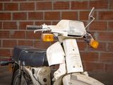 a white motor bike parked in front of a brick wall