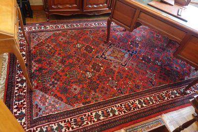 un tapis posé à même le sol dans une pièce où se trouvent un bureau et une chaise