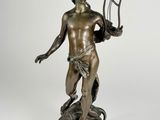 an antique bronze statue of a man holding a pitchfork