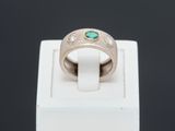 a close up of a ring with a green stone in it