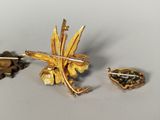 a gold brooch and two other brooches on a table