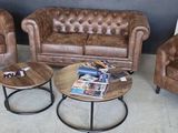 trois fauteuils en cuir marron et une table dans un salon