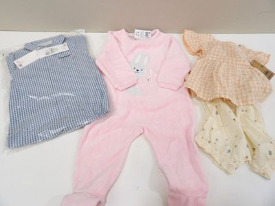 three baby clothes laid out on a white table