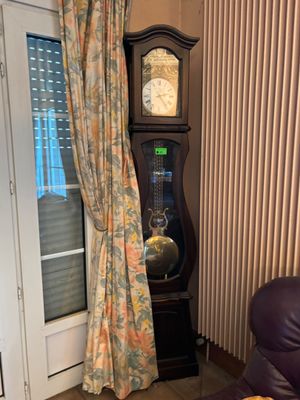 une horloge de parquet dans un coin du salon, près d'une fenêtre