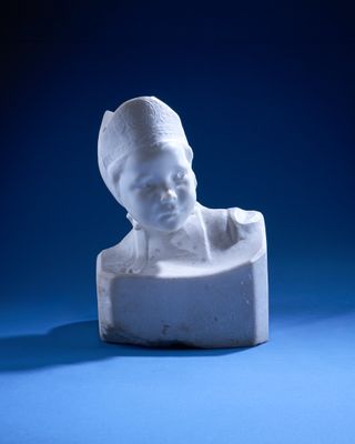 a small white statue of a child on a blue surface