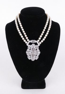 un collier de perles blanches muni d'un fermoir en argent, posé sur un mannequin noir
