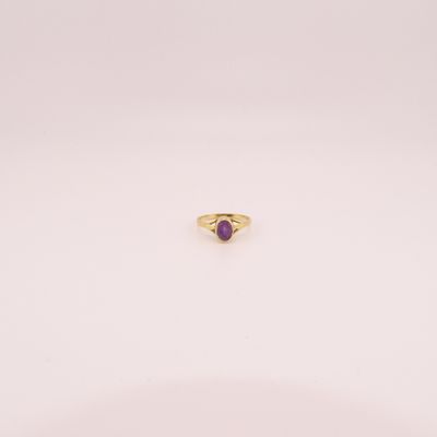 gros plan d'une bague en or avec une pierre violette
