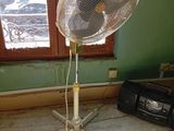 a fan that is sitting on a stand in a room
