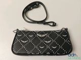 a black and white purse with a wrist strap on a white table