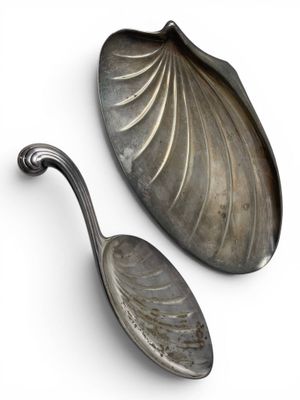 pair of silver spoons on a white surface with a white background