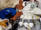 a pile of baby clothes and other items on a bed