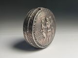 silver coin on a white surface with a shadow on the ground