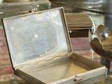 a silver box sitting on a glass table with a bird on it