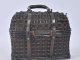 a small wicker bag with a handle on a white surface