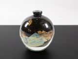 a small glass vase with a black lid on a table