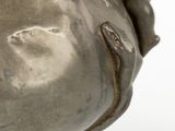 a silver vase with a handle on a white surface