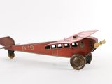a small red toy airplane with wheels on a white surface